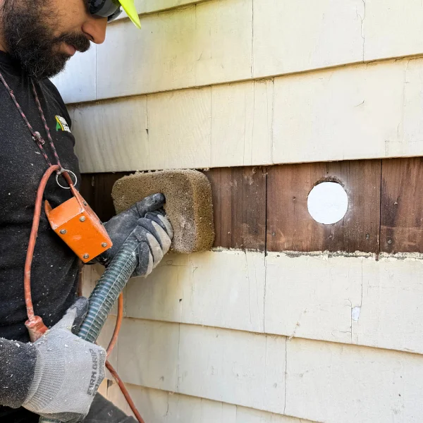 Technician injecting insulation into wall cavity